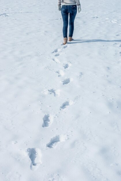 白いセーターを着た女の子が冬に雪に覆われた湖の氷の上を走る