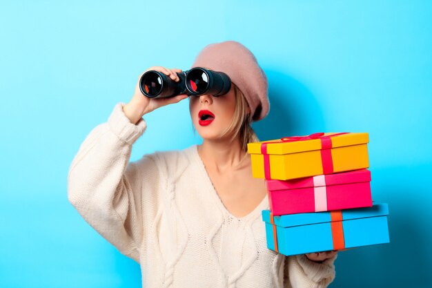 Girl in white sweater with binocular and gift boxes