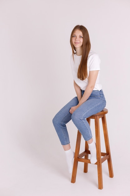 Girl in a white T-shirt and blue jeans on a chair