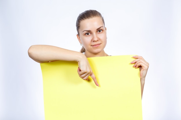 A girl in a white T-shirt is holding a yellow blank large sheet of banner.