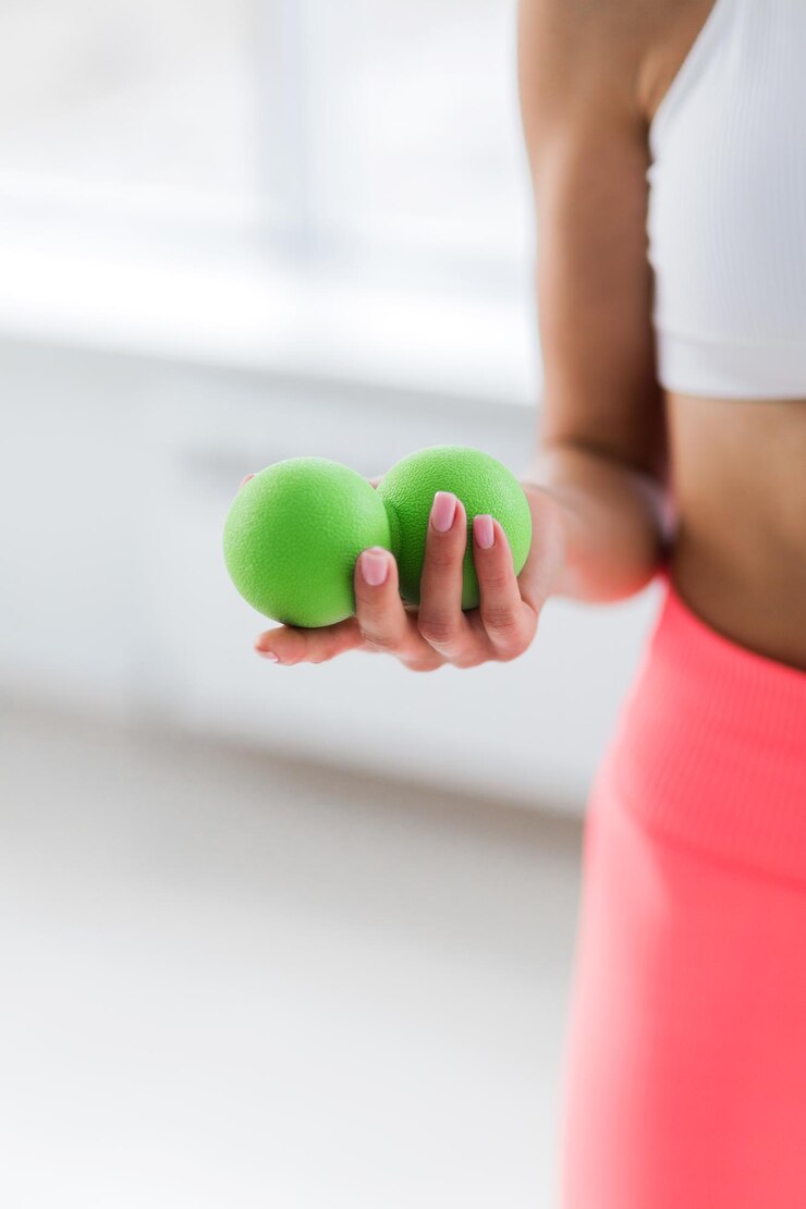Photo a girl in a white top and coralcolored leggings holds a massage ball in her hands