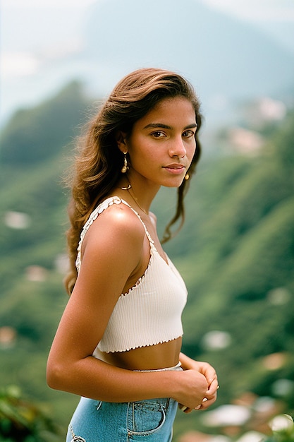 A girl in a white top and a white top stands on a mountain in the caribbean.