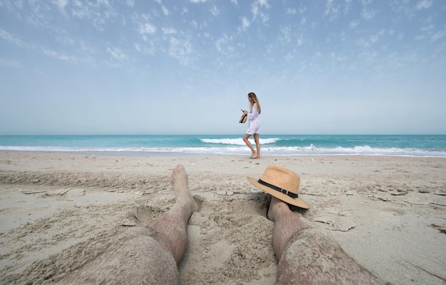 girl in white walking on the beach feet on the sand