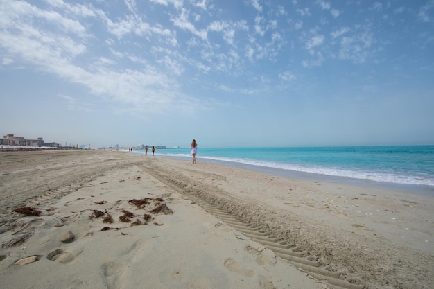 girl in white walking on the beach feet on the sand