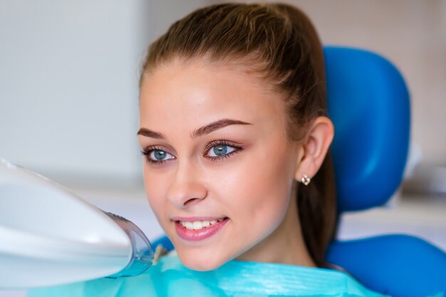 A girl whitens her teeth in dentistry