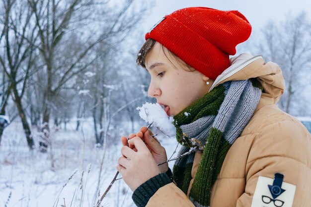 雪をなめる女の子の冬のクローズアップ