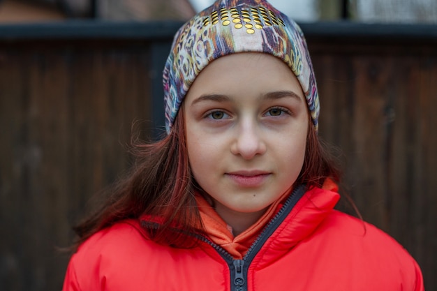 Photo girl in winter clothes. girl 10 years old. teenager in orange jacket. girl on a walk in a hat