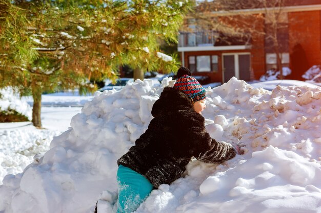 A girl in winter clothes runs to a snow hill with a playing in winter with snow