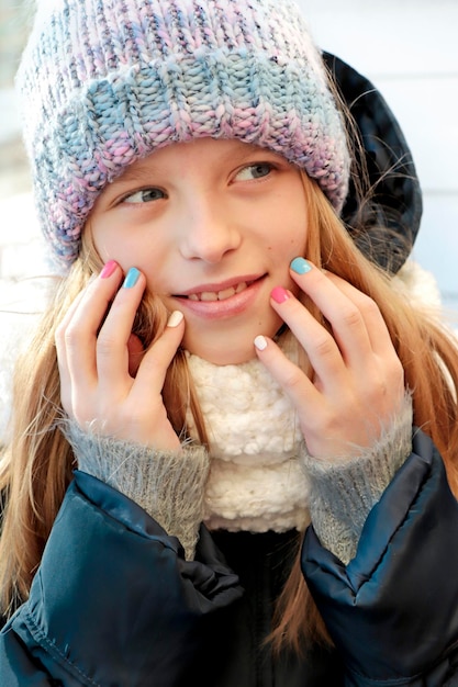 A girl in winter clothes with a multicolored manicure