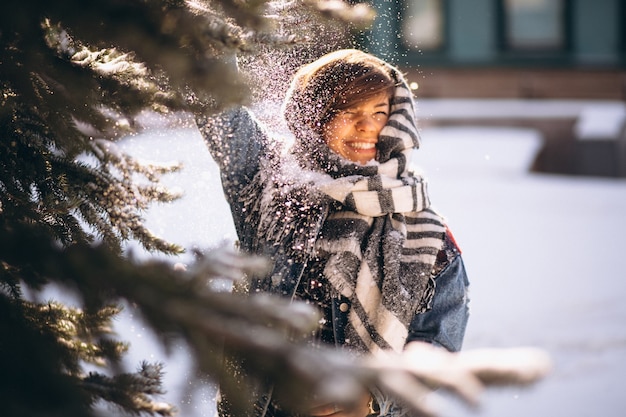 Girl in winter in a denim jacket outdoors by the fir tree