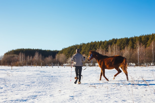 The girl in the winter field is engaged in training with her foal