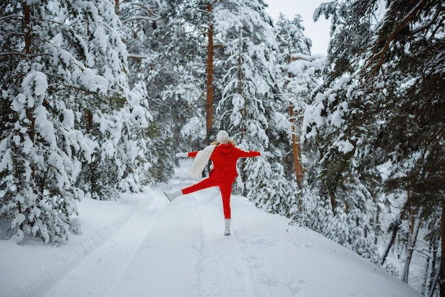 A girl in a winter forest, a blonde in red clothes, a fun walk in nature