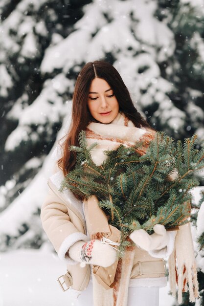 Девушка в зимнем лесу с букетом еловых веток Снежная зима