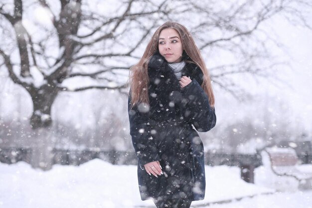Девушка в зимнем парке днем в снегопаде