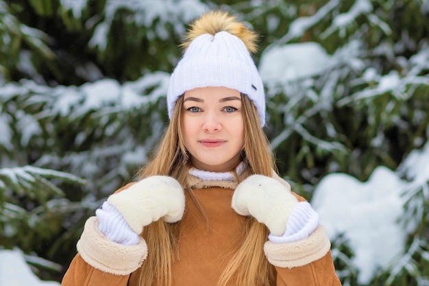 Girl on winter snowy day near christmas tree playing with snow. young woman smiling, playing with snow. wintertime