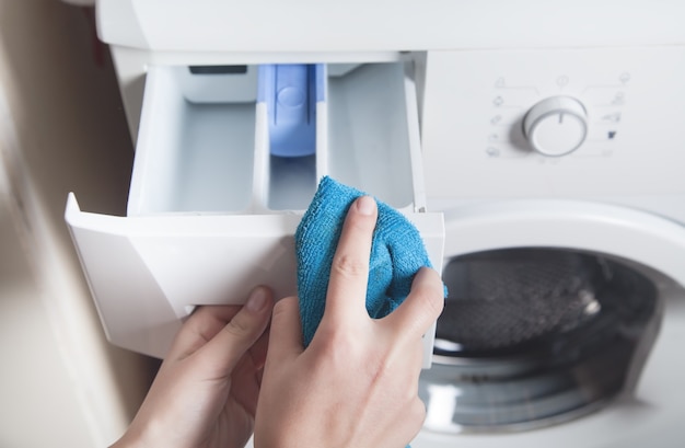 Girl wiping cloth washing machine.