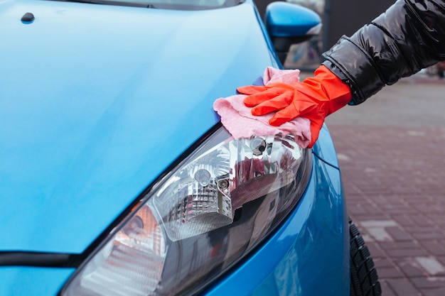 Girl wiping the headlight of a car close-up