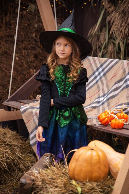 a girl in a witch costume casts a magic over a pumpkin on halloween