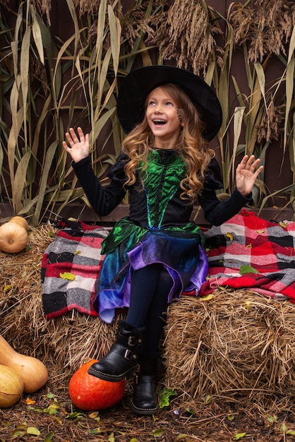 a girl in a witch costume casts a magic over a pumpkin on halloween