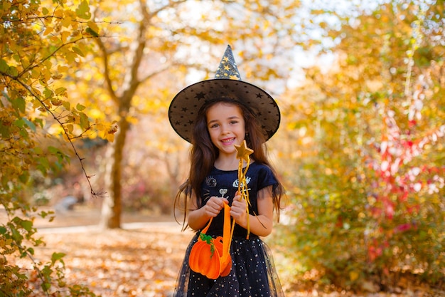 秋の公園でハロウィーンの魔女の衣装を着た女の子