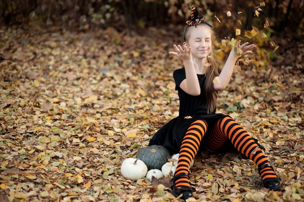 a girl in a witch costume for Halloween the girl throws up the leaves