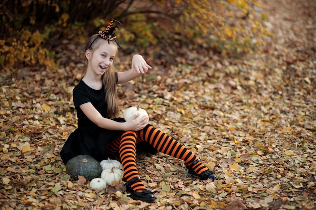 A girl in a witch costume for Halloween a girl with pumpkins the girl laughs