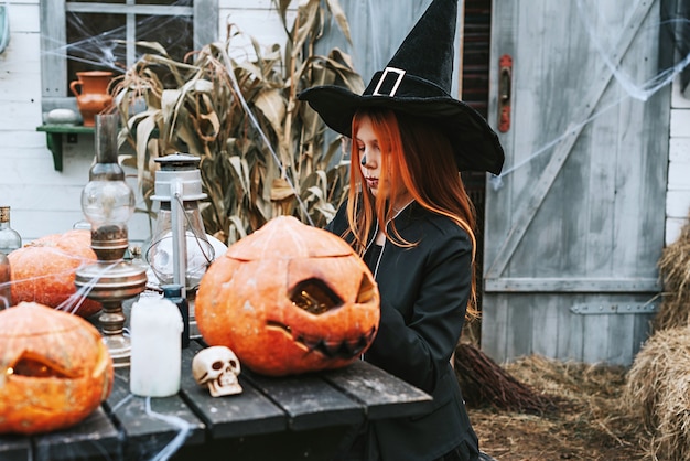 A girl in a witch costume having fun at a Halloween party on the decorated porch