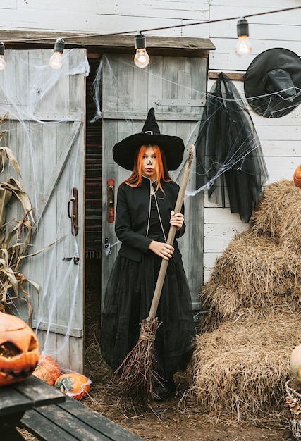 Girl in a witch costume with a broom at a Halloween party