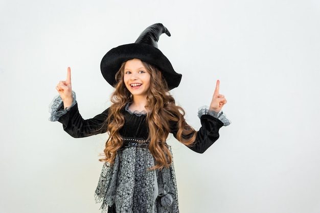 A girl in a witch's outfit points to an advertisement A beautiful enchantress on an isolated background Wizard's Halloween outfit