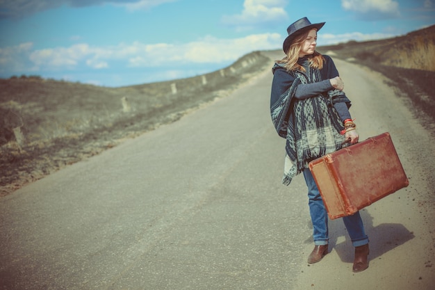 写真 道路上のスーツケースを持つ少女