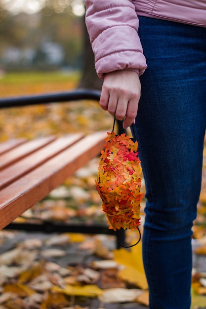 Ragazza con maschera antivirale con foglie di autunno nel parco