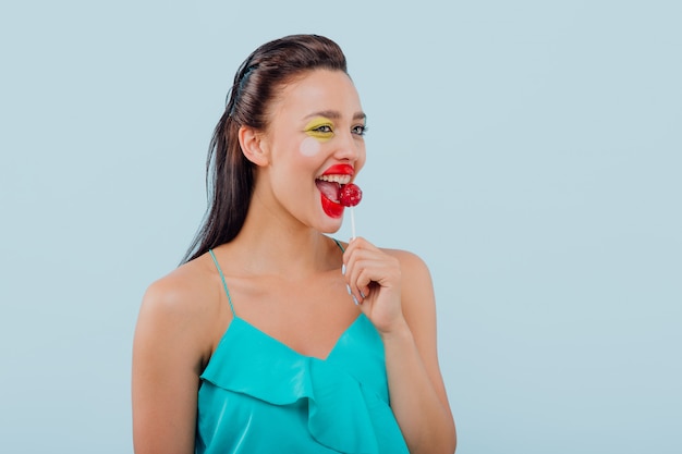 Photo girl with artsy make up licks a lollipop