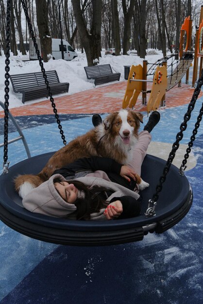 Photo a girl with australian shepherd red merle on playground in winter has fun and enjoy