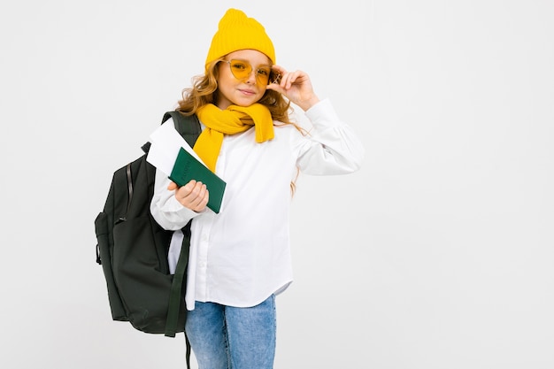 Girl with a backpack on her shoulders holds a passport with tickets for the rest on a white background with copy space.