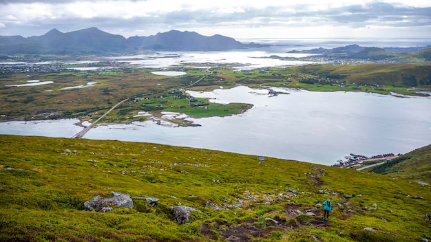 ノルウェーのロフォーテン諸島のパノラマを眺めながら、Offersykammen トレイル ヘッドをハイキングするバックパックを持つ少女