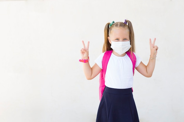 Girl with a backpack in a mask.School