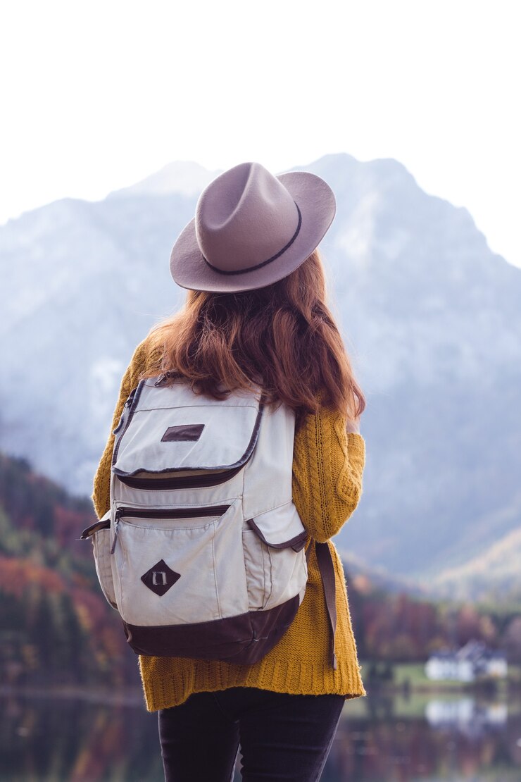 Photo girl with a backpack stands on the shore of a mountain lake