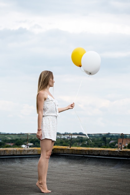 Girl with balloons on the roof of the house