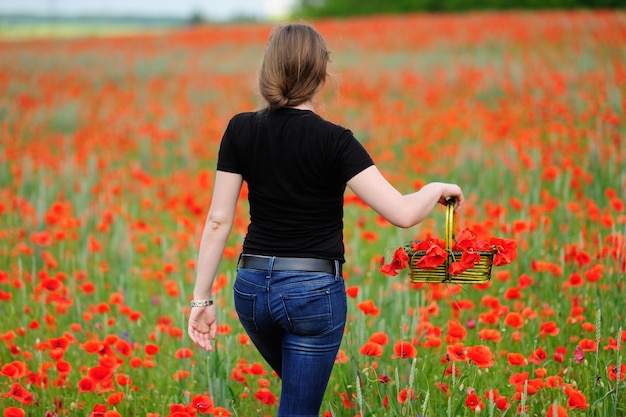 Girl with basket on poppy field