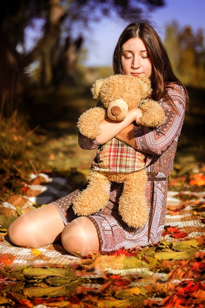 A girl with a bear in the fall leaves