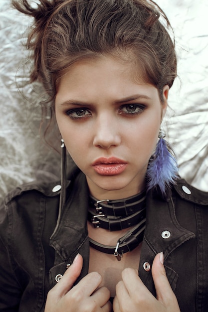 Girl with beautiful eyes in a black denim jacket on a silver wall background