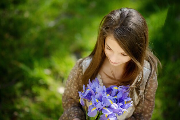 Girl with beautiful hair with a bouquet of purple irises. View from above. Soft focus.