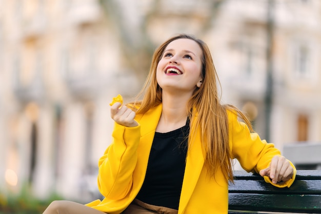 Girl with a beautiful makeup in a yellow coat holds a dessert in