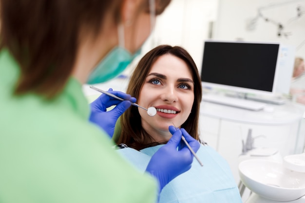 Girl with a beautiful smile at the dentist's appointment. Dentist examines a patient’s teeth