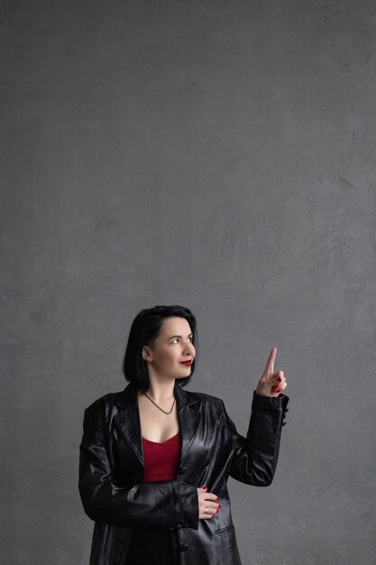 Girl with black hair red lipstick in leather jacket looks away