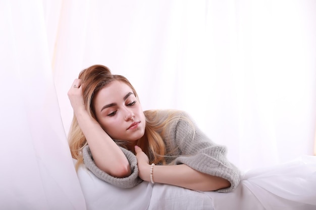 Girl with blond hair and gray sweater poses