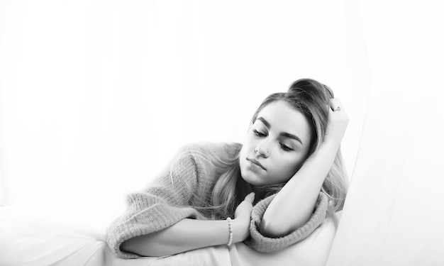 Girl with blond hair and gray sweater poses