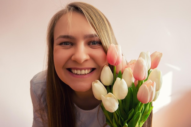 girl with blond long loose hair keeps spring flowers in the hands