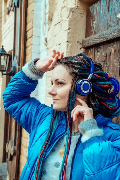 Girl with blue dreadlocks listening to music on headphones