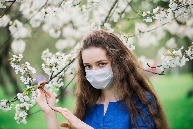 Photo girl with blue eyes in mask in blossom park.